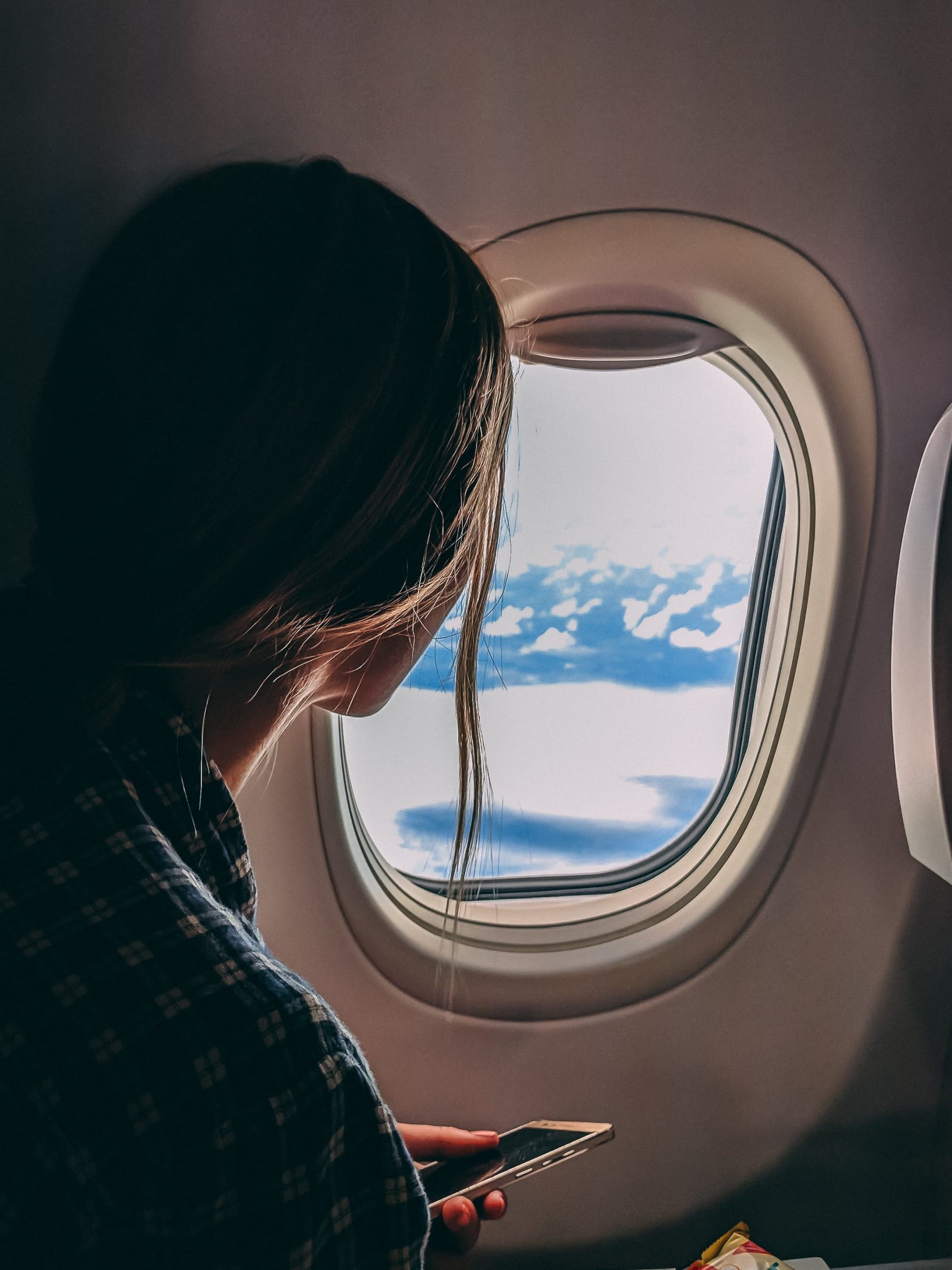 Person holding smartphone riding airplane 2033343 scaled.jpg
